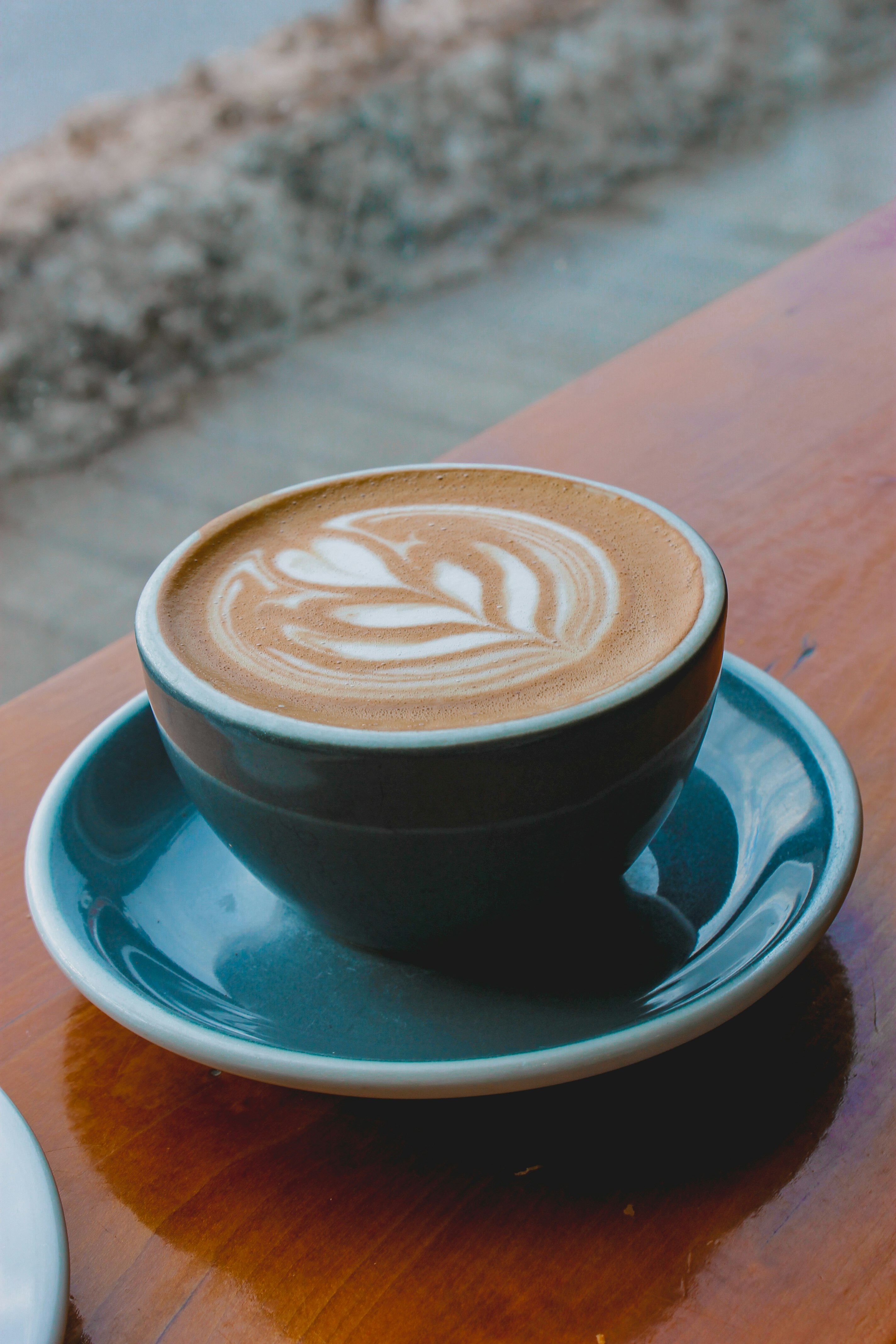 black ceramic cup with saucer on brown wooden table